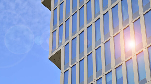 Abstract closeup of the glass-clad facade of a modern building covered in reflective plate glass. Architecture abstract background. Glass wall and facade detail.