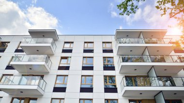 Çevre mimarisi. Yeşil ağaç ve yeni apartman. Doğanın ve modernliğin ahengi. Yeşil yerleşim bölgesinde yeni daireleri olan modern bir yerleşim yeri.. 