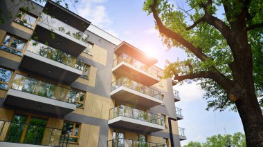 Çevre mimarisi. Yeşil ağaç ve yeni apartman. Doğanın ve modernliğin ahengi. Yeşil yerleşim bölgesinde yeni daireleri olan modern bir yerleşim yeri.. 