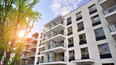 Çevre mimarisi. Yeşil ağaç ve yeni apartman. Doğanın ve modernliğin ahengi. Yeşil yerleşim bölgesinde yeni daireleri olan modern bir yerleşim yeri.. 