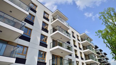 Çevre mimarisi. Yeşil ağaç ve yeni apartman. Doğanın ve modernliğin ahengi. Yeşil yerleşim bölgesinde yeni daireleri olan modern bir yerleşim yeri.. 