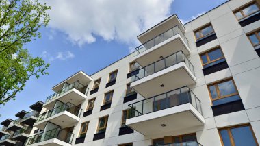 Çevre mimarisi. Yeşil ağaç ve yeni apartman. Doğanın ve modernliğin ahengi. Yeşil yerleşim bölgesinde yeni daireleri olan modern bir yerleşim yeri.. 