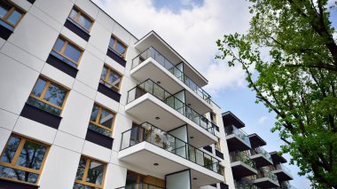 Çevre mimarisi. Yeşil ağaç ve yeni apartman. Doğanın ve modernliğin ahengi. Yeşil yerleşim bölgesinde yeni daireleri olan modern bir yerleşim yeri.. 