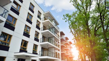 Çevre mimarisi. Yeşil ağaç ve yeni apartman. Doğanın ve modernliğin ahengi. Yeşil yerleşim bölgesinde yeni daireleri olan modern bir yerleşim yeri.. 