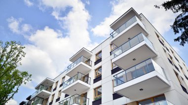 Çevre mimarisi. Yeşil ağaç ve yeni apartman. Doğanın ve modernliğin ahengi. Yeşil yerleşim bölgesinde yeni daireleri olan modern bir yerleşim yeri.. 