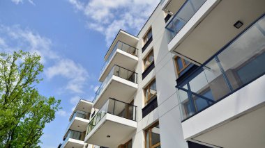 Çevre mimarisi. Yeşil ağaç ve yeni apartman. Doğanın ve modernliğin ahengi. Yeşil yerleşim bölgesinde yeni daireleri olan modern bir yerleşim yeri.. 