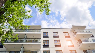 Çevre mimarisi. Yeşil ağaç ve yeni apartman. Doğanın ve modernliğin ahengi. Yeşil yerleşim bölgesinde yeni daireleri olan modern bir yerleşim yeri.. 