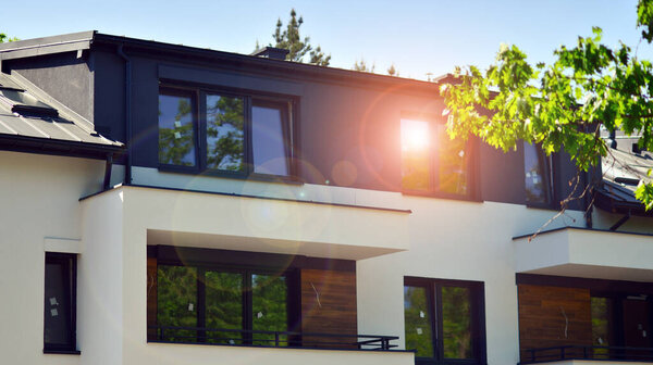 Terraced family homes in newly developed housing estate. The real estate market in the suburbs. New single family houses in a new development area. Residential homes with modern facade. 