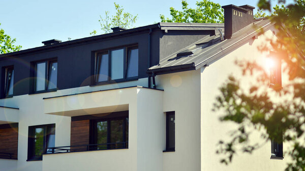 Terraced family homes in newly developed housing estate. The real estate market in the suburbs. New single family houses in a new development area. Residential homes with modern facade. 