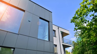 Grafit cephe ve mavi gökyüzüne karşı ofis binasının bir parçası üzerinde geniş pencereler. Pencereli modern alüminyum kaplama cephesi.