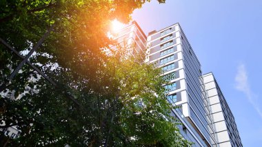 Yeşil yerleşim bölgesinde yeni daireleri olan modern bir yerleşim yeri. Çevre mimarisi. Yeşil ağaç ve yeni apartman. Doğanın ve modernliğin ahengi.