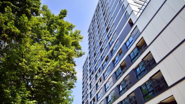 Modern residential building with new apartments in a green residential area. Eco architecture. Green tree and new apartment building. The harmony of nature and modernity.