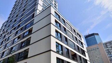 Mavi gökyüzü olan güneşli bir günde modern bir apartman. Modern bir apartmanın ön cephesi. Güneş ışığıyla kaplı cam yüzey. Ufukta yükselen güneş.