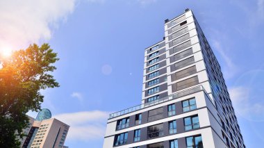 Yeşil yerleşim bölgesinde yeni daireleri olan modern bir yerleşim yeri. Çevre mimarisi. Yeşil ağaç ve yeni apartman. Doğanın ve modernliğin ahengi.