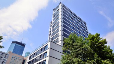 Modern residential building with new apartments in a green residential area. Eco architecture. Green tree and new apartment building. The harmony of nature and modernity.