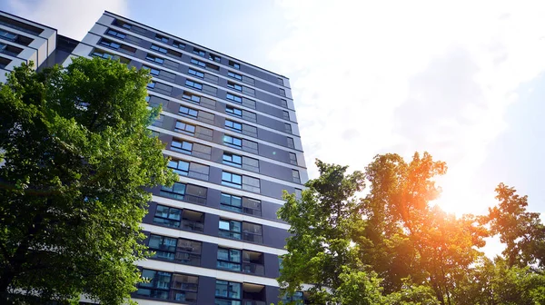 Modern residential building with new apartments in a green residential area. Eco architecture. Green tree and new apartment building. The harmony of nature and modernity.