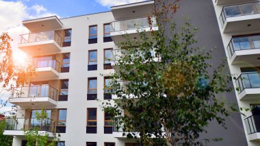 Gündüz gözüyle modern yerleşim yerinin dış tarafında. Mavi gökyüzü olan güneşli bir günde modern apartman binaları. Modern bir apartmanın cephesi. 