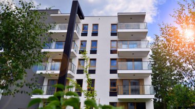 Gündüz gözüyle modern yerleşim yerinin dış tarafında. Mavi gökyüzü olan güneşli bir günde modern apartman binaları. Modern bir apartmanın cephesi. 