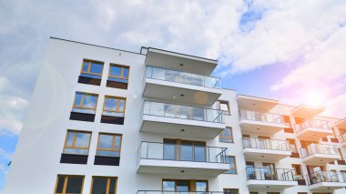 Gündüz gözüyle modern yerleşim yerinin dış tarafında. Mavi gökyüzü olan güneşli bir günde modern apartman binaları. Modern bir apartmanın cephesi. 