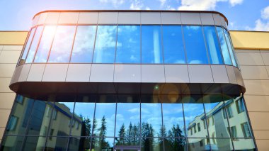 Mavi gökyüzüne karşı modern ofis binası. Modern cam bir binanın pencereleri. Ticari binalara bakıyorum..