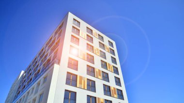 Gündüz gözüyle modern yerleşim yerinin dış tarafında. Mavi gökyüzü olan güneşli bir günde modern apartman binaları. Modern bir apartmanın cephesi. 