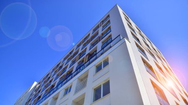 Gündüz gözüyle modern yerleşim yerinin dış tarafında. Mavi gökyüzü olan güneşli bir günde modern apartman binaları. Modern bir apartmanın cephesi. 