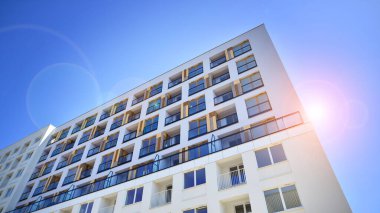 Gündüz gözüyle modern yerleşim yerinin dış tarafında. Mavi gökyüzü olan güneşli bir günde modern apartman binaları. Modern bir apartmanın cephesi. 