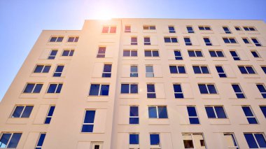 Gündüz gözüyle modern yerleşim yerinin dış tarafında. Mavi gökyüzü olan güneşli bir günde modern apartman binaları. Modern bir apartmanın cephesi. 