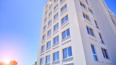 Gündüz gözüyle modern yerleşim yerinin dış tarafında. Mavi gökyüzü olan güneşli bir günde modern apartman binaları. Modern bir apartmanın cephesi. 