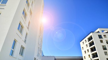 Gündüz gözüyle modern yerleşim yerinin dış tarafında. Mavi gökyüzü olan güneşli bir günde modern apartman binaları. Modern bir apartmanın cephesi. 