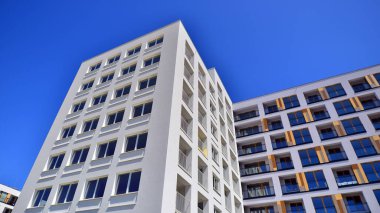 Gündüz gözüyle modern yerleşim yerinin dış tarafında. Mavi gökyüzü olan güneşli bir günde modern apartman binaları. Modern bir apartmanın cephesi. 
