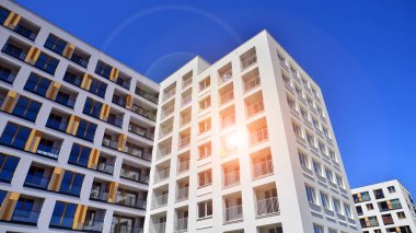 Gündüz gözüyle modern yerleşim yerinin dış tarafında. Mavi gökyüzü olan güneşli bir günde modern apartman binaları. Modern bir apartmanın cephesi. 