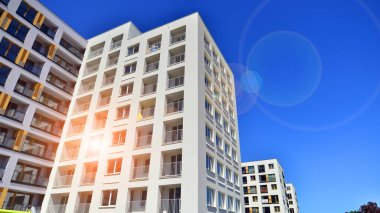 Gündüz gözüyle modern yerleşim yerinin dış tarafında. Mavi gökyüzü olan güneşli bir günde modern apartman binaları. Modern bir apartmanın cephesi. 