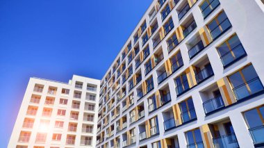 Gündüz gözüyle modern yerleşim yerinin dış tarafında. Mavi gökyüzü olan güneşli bir günde modern apartman binaları. Modern bir apartmanın cephesi. 