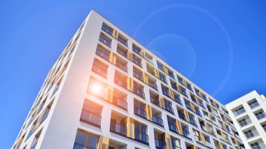 Gündüz gözüyle modern yerleşim yerinin dış tarafında. Mavi gökyüzü olan güneşli bir günde modern apartman binaları. Modern bir apartmanın cephesi. 