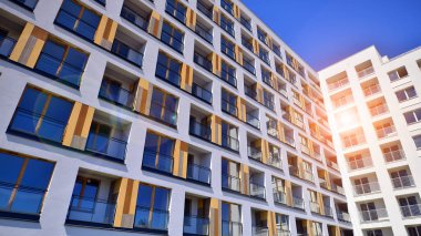 Gündüz gözüyle modern yerleşim yerinin dış tarafında. Mavi gökyüzü olan güneşli bir günde modern apartman binaları. Modern bir apartmanın cephesi. 