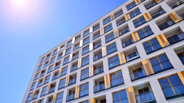 Gündüz gözüyle modern yerleşim yerinin dış tarafında. Mavi gökyüzü olan güneşli bir günde modern apartman binaları. Modern bir apartmanın cephesi. 