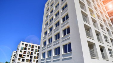 Gündüz gözüyle modern yerleşim yerinin dış tarafında. Mavi gökyüzü olan güneşli bir günde modern apartman binaları. Modern bir apartmanın cephesi. 