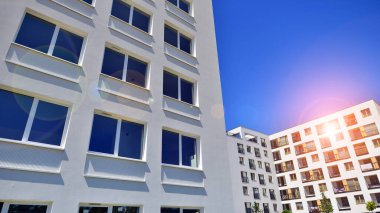 Gündüz gözüyle modern yerleşim yerinin dış tarafında. Mavi gökyüzü olan güneşli bir günde modern apartman binaları. Modern bir apartmanın cephesi. 