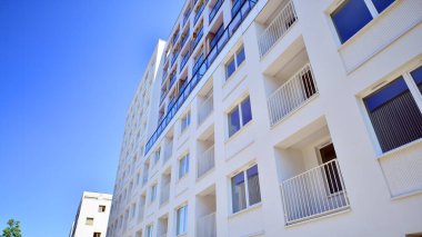 Gündüz gözüyle modern yerleşim yerinin dış tarafında. Mavi gökyüzü olan güneşli bir günde modern apartman binaları. Modern bir apartmanın cephesi. 