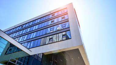 Mavi gökyüzüne karşı modern ofis binası. Modern cam bir binanın pencereleri. Ticari binalara bakıyorum..