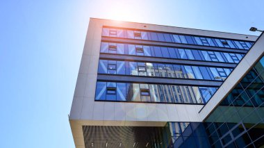 Mavi gökyüzüne karşı modern ofis binası. Modern cam bir binanın pencereleri. Ticari binalara bakıyorum..