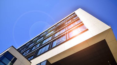 Mavi gökyüzüne karşı modern ofis binası. Modern cam bir binanın pencereleri. Ticari binalara bakıyorum..