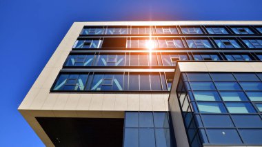 Mavi gökyüzüne karşı modern ofis binası. Modern cam bir binanın pencereleri. Ticari binalara bakıyorum..