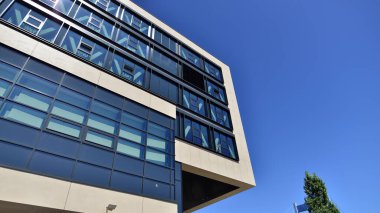 Mavi gökyüzüne karşı modern ofis binası. Modern cam bir binanın pencereleri. Ticari binalara bakıyorum..