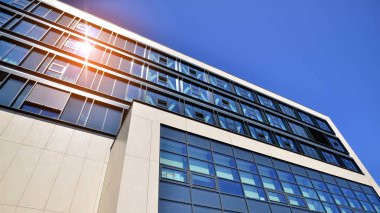 Mavi gökyüzüne karşı modern ofis binası. Modern cam bir binanın pencereleri. Ticari binalara bakıyorum..