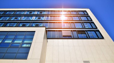 Mavi gökyüzüne karşı modern ofis binası. Modern cam bir binanın pencereleri. Ticari binalara bakıyorum..