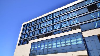 Mavi gökyüzüne karşı modern ofis binası. Modern cam bir binanın pencereleri. Ticari binalara bakıyorum..