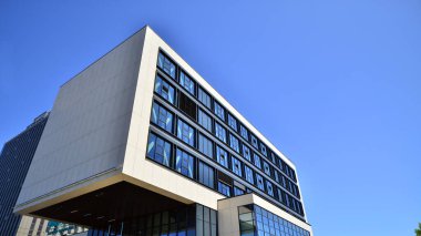 Mavi gökyüzüne karşı modern ofis binası. Modern cam bir binanın pencereleri. Ticari binalara bakıyorum..
