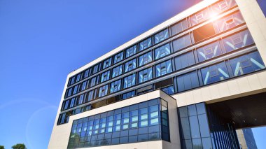 Mavi gökyüzüne karşı modern ofis binası. Modern cam bir binanın pencereleri. Ticari binalara bakıyorum..
